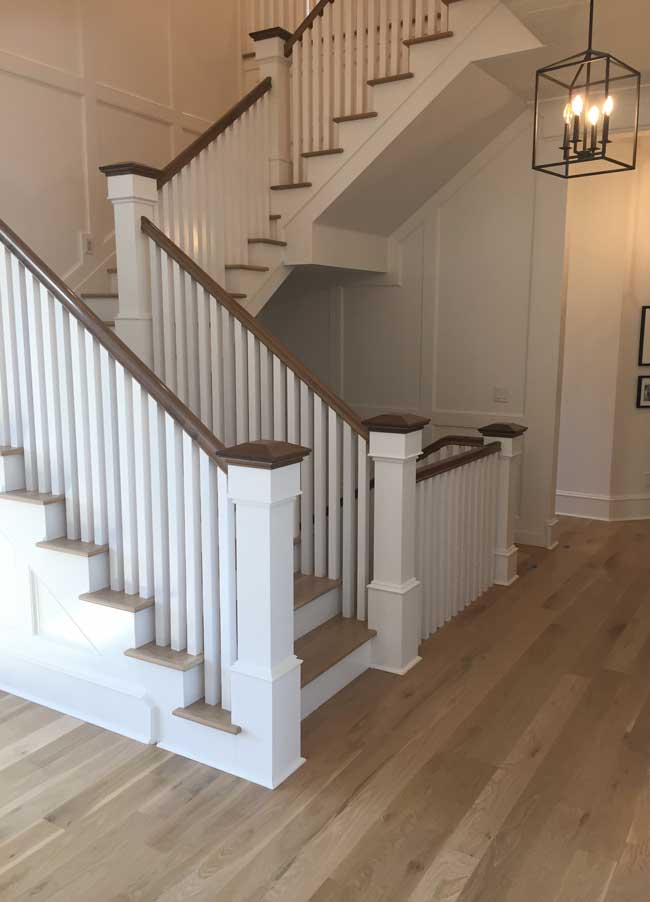 new hardwood floors in hallway and up stairs with white railings and brown top accents