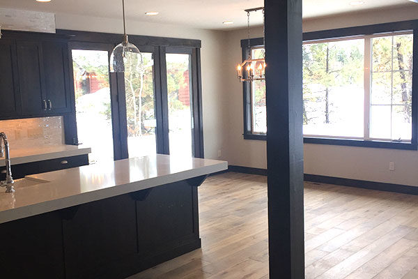 engineered hardwood flooring in new home in kitchen and living room with black cupboards and black accent beams