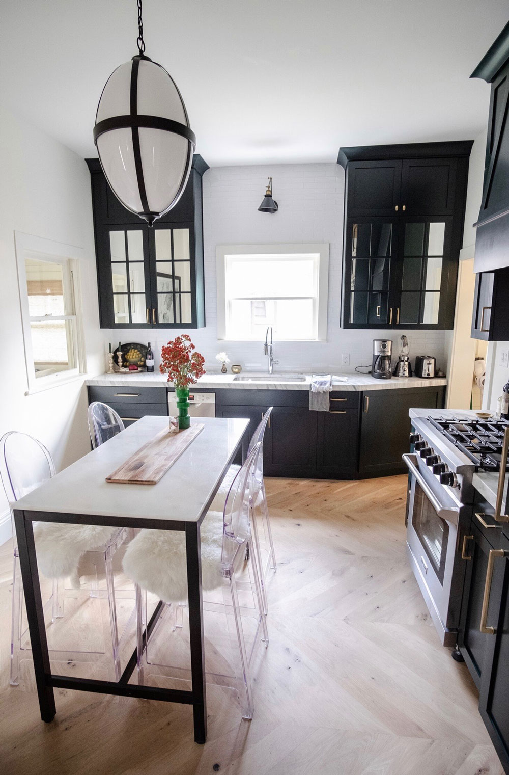 hardwood flooring in modern kitchen with black cupboards, white countertops, and gold accents