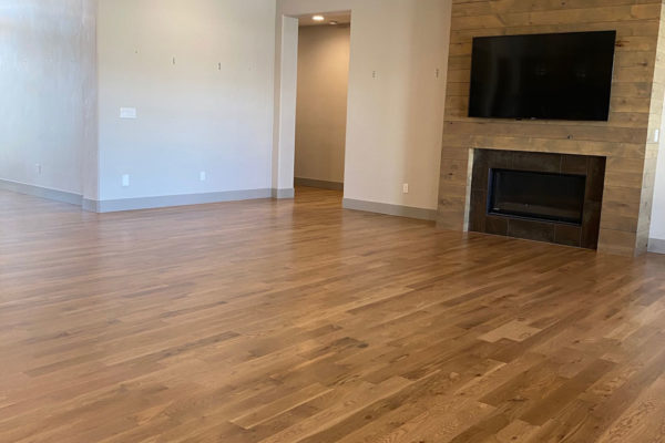 brown oak hardwood floors in modern living room with fireplace and tv