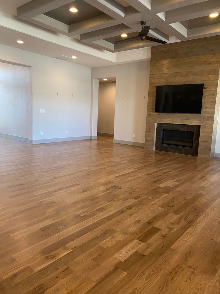 brown oak hardwood floors in modern living room with fireplace and tv